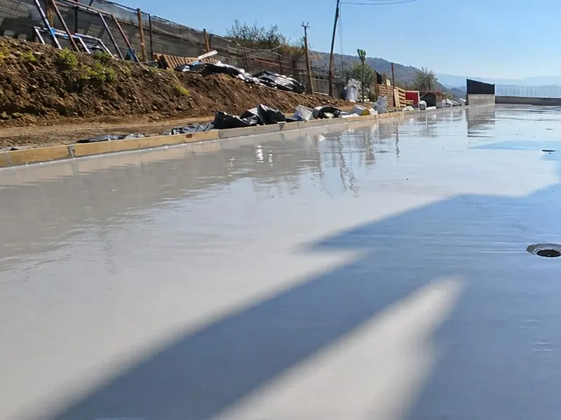Losa con membrana líquida recién aplicada, brillante, reflejando el cielo