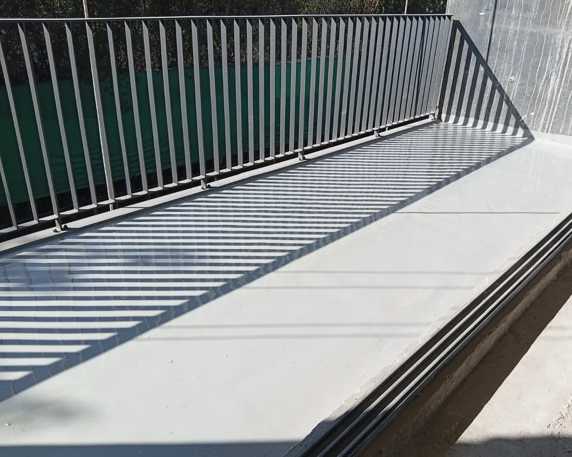 Balcón impermeabilizado con la sombra de la baranda proyectada sobre la membrana gris